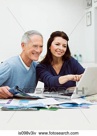Mature couple using laptop to book vacation View Large Photo Image Stock Photo - Mature couple using laptop to book vacation. Fotosearch