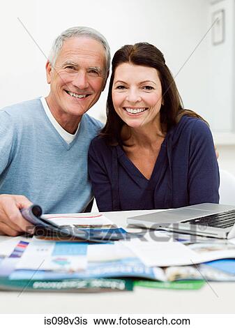 Mature couple using laptop to book vacation View Large Photo Image Stock Photograph - Mature couple using laptop to book vacation. Fotosearch
