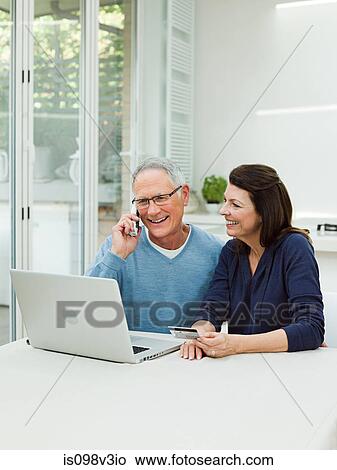 Mature couple using laptop with credit card View Large Photo Image Picture - Mature couple using laptop with credit card. Fotosearch