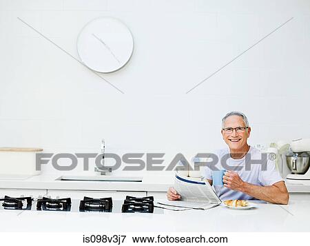 Senior man having breakfast, reading newspaper View Large Photo Image Stock Photo - Senior man having breakfast, reading newspaper. Fotosearch