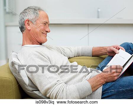 Senior man sitting on sofa reading book View Large Photo Image Stock Photography - Senior man sitting on sofa reading book. Fotosearch