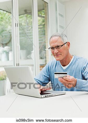 Picture - Senior man using laptop with credit card. Fotosearch