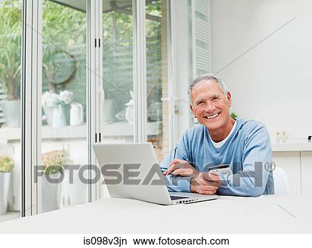 Senior man using laptop with credit card View Large Photo Image Picture - Senior man using laptop with credit card. Fotosearch