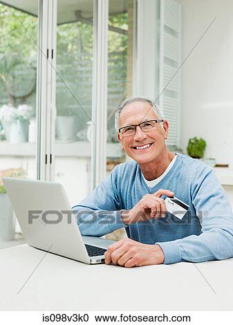 Senior man using laptop with credit card View Large Photo Image Stock Image - Senior man using laptop with credit card. Fotosearch