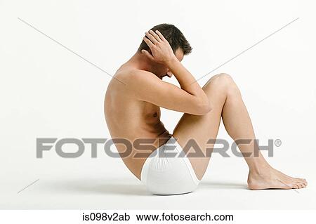 Stock Image - Young man doing sit ups. Fotosearch