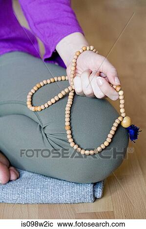 Stock Image - Woman kneeling holding beads. Fotosearch