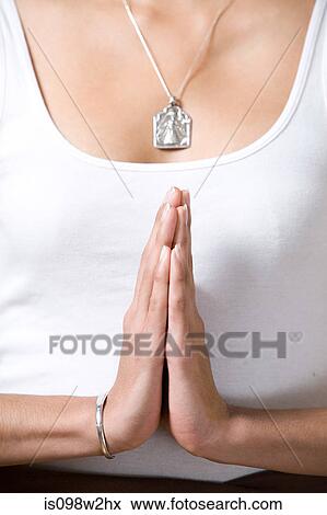 Stock Photo - Woman wearing silver pendant in prayer position during yoga. Fotosearch