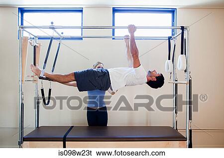 Man doing pilates with instructor View Large Photo Image Stock Photograph - Man doing pilates with instructor. Fotosearch