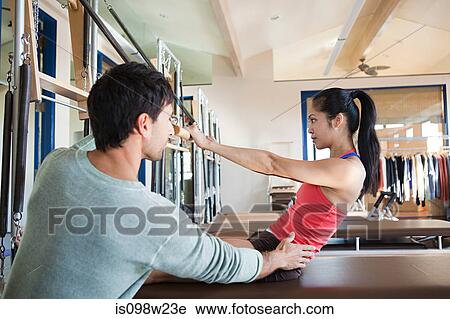 Pilates instructor assisting woman View Large Photo Image Stock Image - Pilates instructor assisting woman. Fotosearch