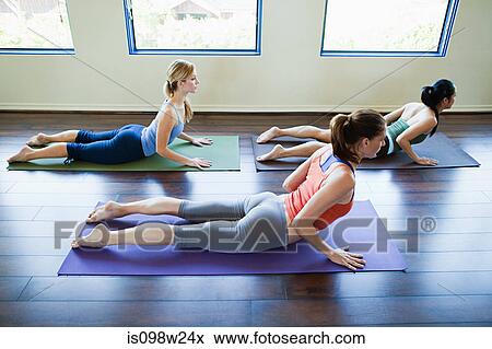 Three woman doing cobra pose in yoga class View Large Photo Image Stock Photo - Three woman doing cobra pose in yoga class. Fotosearch