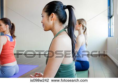 Stock Image - Three women doing yoga class. Fotosearch