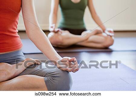 Picture - Two women doing yoga class. Fotosearch