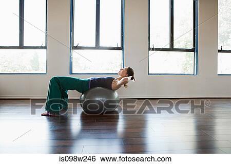 Stock Photograph - Woman doing sit ups on exercise ball. Fotosearch