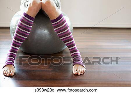 Picture - Woman wearing stripey legwarmers sitting on exercise ball. Fotosearch