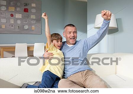 Father and son watching television cheering View Large Photo Image Stock Image - Father and son watching television cheering. Fotosearch