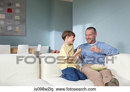 Father and son watching television eating popcorn View Large Photo Image Stock Photography - Father and son watching television eating popcorn. Fotosearch