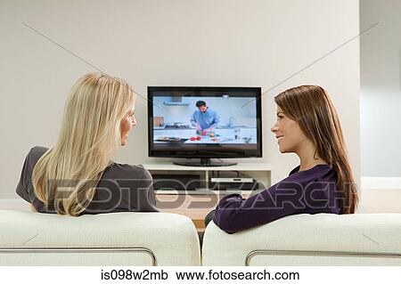 Two young women watching television View Large Photo Image Stock Image - Two young women watching television. Fotosearch