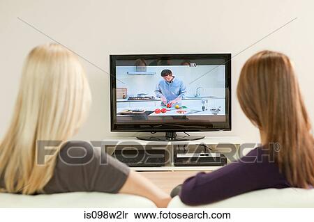 Two young women watching television View Large Photo Image Stock Photography - Two young women watching television. Fotosearch