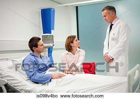 Wife visiting husband in hospital, talking to doctor View Large Photo Image Picture - Wife visiting husband in hospital, talking to doctor. Fotosearch
