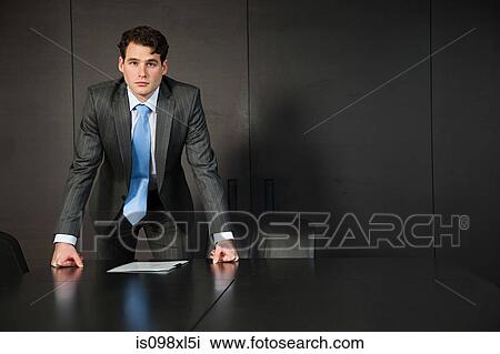 Businessman leaning on conference table with documents View Large Photo Image Stock Image - Businessman leaning on conference table with documents. Fotosearch