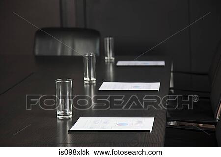 Stock Image - Conference table with drinking glasses and documents. Fotosearch