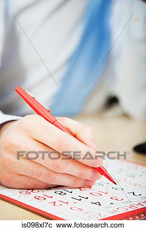 Stock Image - Office worker marking calendar with red pen. Fotosearch