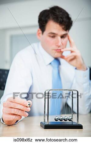 Office worker playing with newtons cradle View Large Photo Image Stock Photo - Office worker playing with newtons cradle. Fotosearch