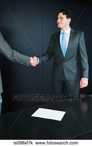 Stock Image - Two businessmen shaking hands at job interview. Fotosearch