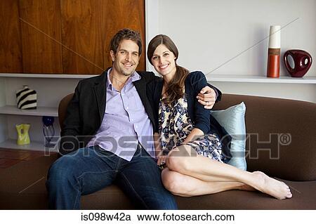 Couple sitting on sofa, portrait View Large Photo Image Stock Image - Couple sitting on sofa, portrait. Fotosearch