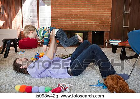 Father lifting son in living room View Large Photo Image Stock Image - Father lifting son in living room. Fotosearch