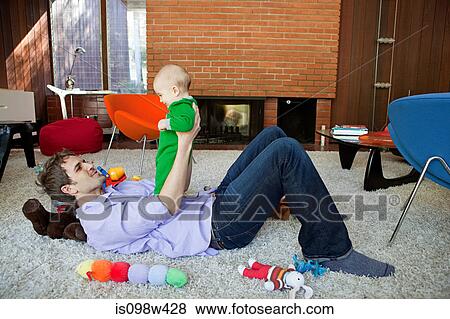 Father playing with baby son in living room View Large Photo Image Stock Photo - Father playing with baby son in living room. Fotosearch