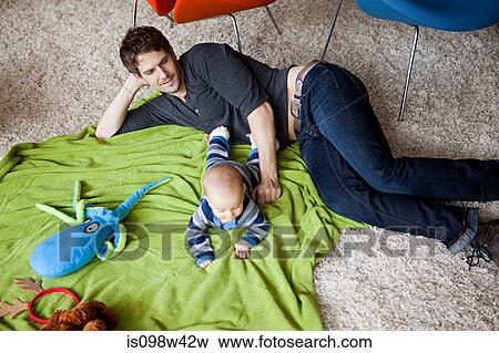 Stock Photo - Father playing with baby son in living room. Fotosearch