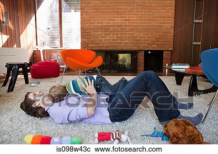 Father playing with son in living room View Large Photo Image Stock Image - Father playing with son in living room. Fotosearch