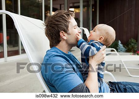 Father with baby son sitting on lounge chair View Large Photo Image Stock Image - Father with baby son sitting on lounge chair. Fotosearch