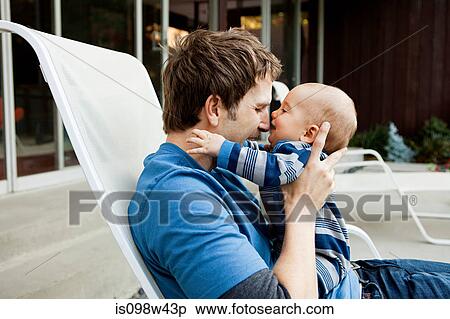 Father with baby son sitting on lounge chair View Large Photo Image Stock Photography - Father with baby son sitting on lounge chair. Fotosearch