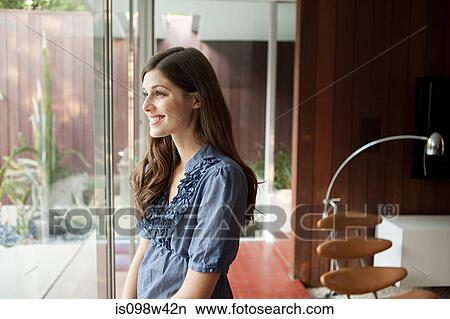Happy young woman looking through window View Large Photo Image Picture - Happy young woman looking through window. Fotosearch