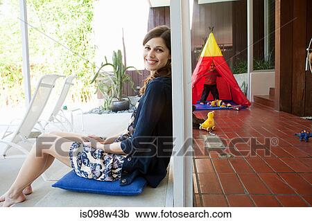 Stock Image - Mother at home with son playing in background. Fotosearch