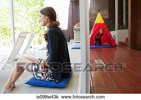 Mother at home with son playing in background View Large Photo Image Stock Image - Mother at home with son playing in background. Fotosearch