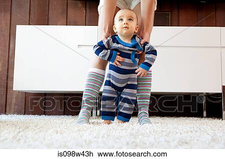 Mother helping baby son take first steps View Large Photo Image Stock Image - Mother helping baby son take first steps. Fotosearch