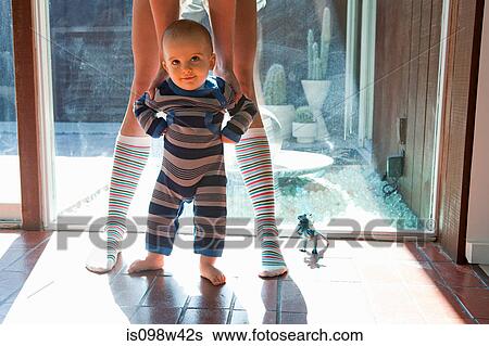 Stock Photograph - Mother helping baby son take first steps. Fotosearch