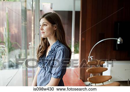 Young woman looking out of window View Large Photo Image Stock Image - Young woman looking out of window. Fotosearch
