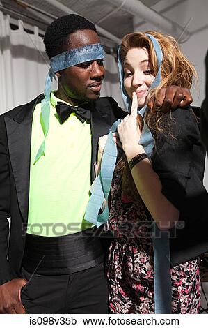 Stock Image - Couple at party, man with streamer covering eyes. Fotosearch
