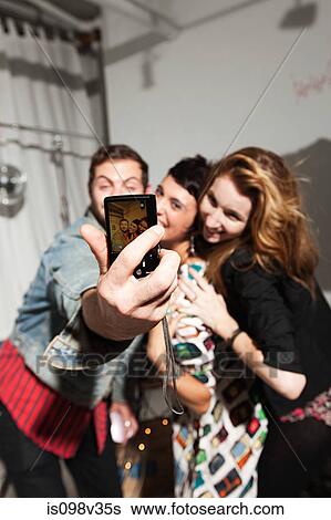 Stock Photograph - Friends photographing themselves at party. Fotosearch