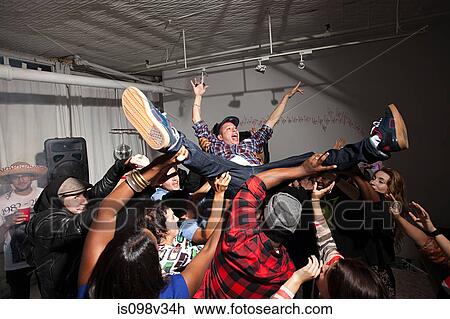 Stock Image - Man crowd surfing at party. Fotosearch