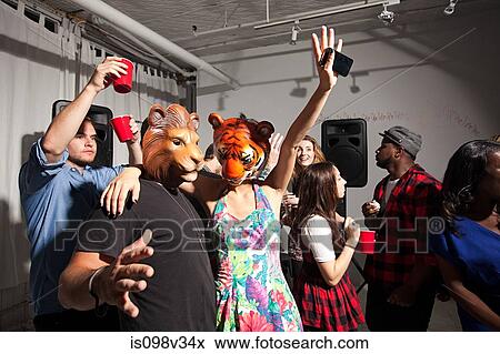 Stock Photo - People wearing lion and tiger masks dancing at party. Fotosearch