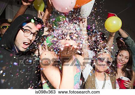 Stock Image - Woman blowing glitter at party. Fotosearch