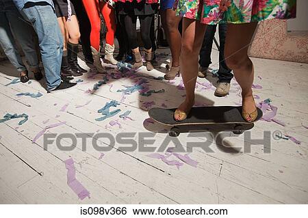 Woman standing on skateboard at party View Large Photo Image Stock Photograph - Woman standing on skateboard at party. Fotosearch