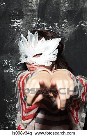 Woman wearing mask at party, pointing at camera View Large Photo Image Stock Photography - Woman wearing mask at party, pointing at camera. Fotosearch