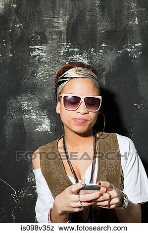 Stock Photo - Woman wearing sunglasses texting at party. Fotosearch