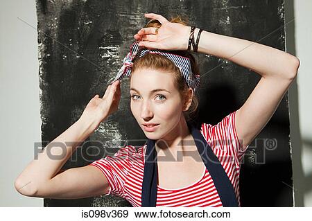 Stock Photo - Young woman adjusting hair accessory at party. Fotosearch